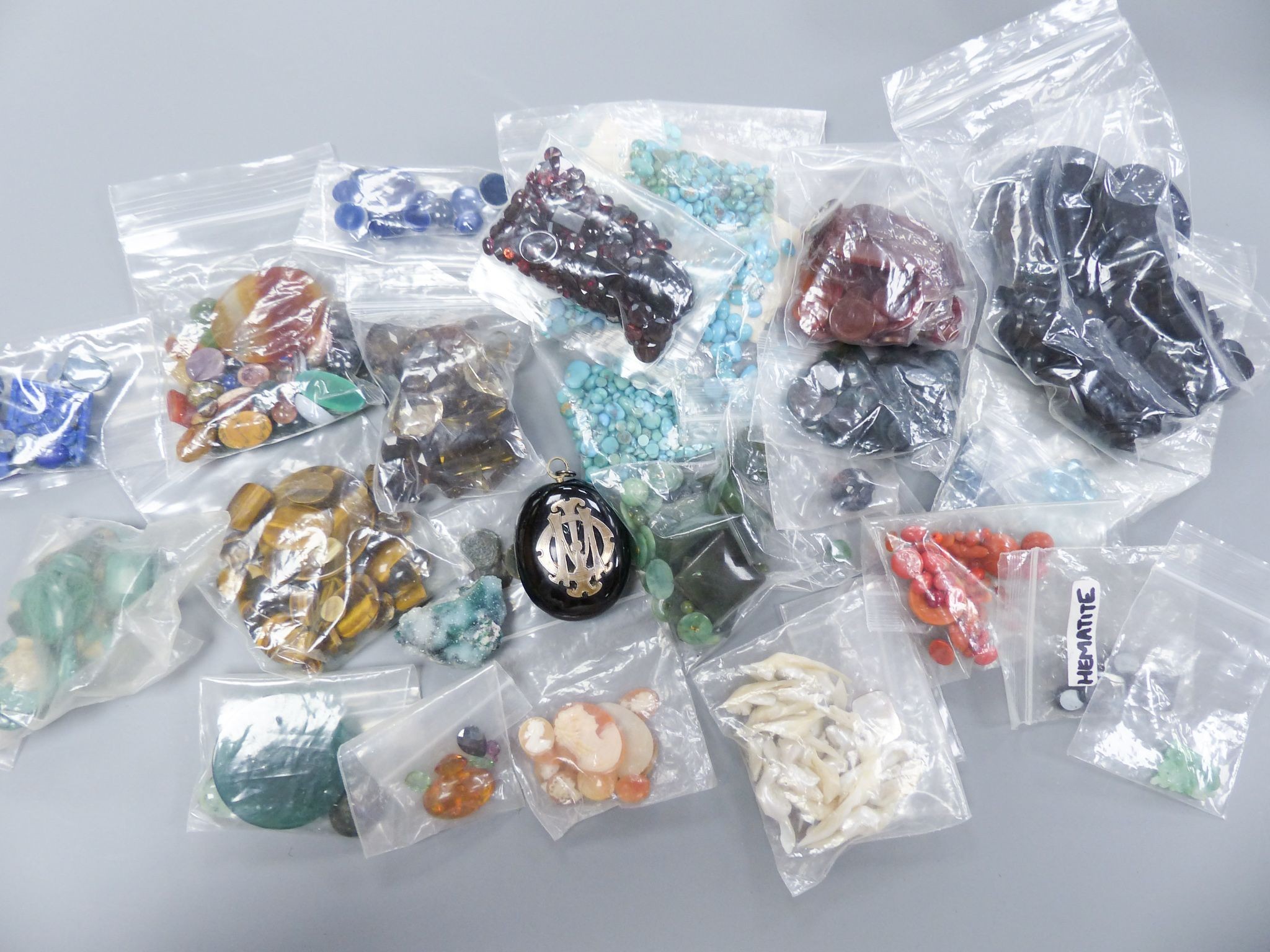 A quantity of assorted unmounted gemstones including, opal, opal doublet, malachite, chalcedony, tiger's eye quartz, hematite, etc.